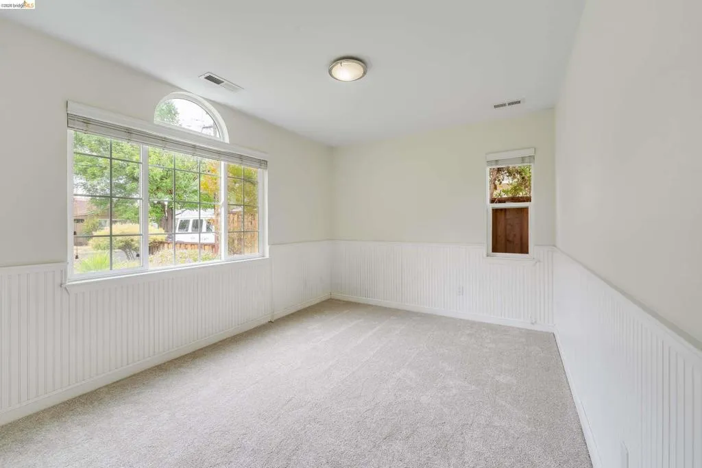 Carpeted room with a large window featuring a half-round transom