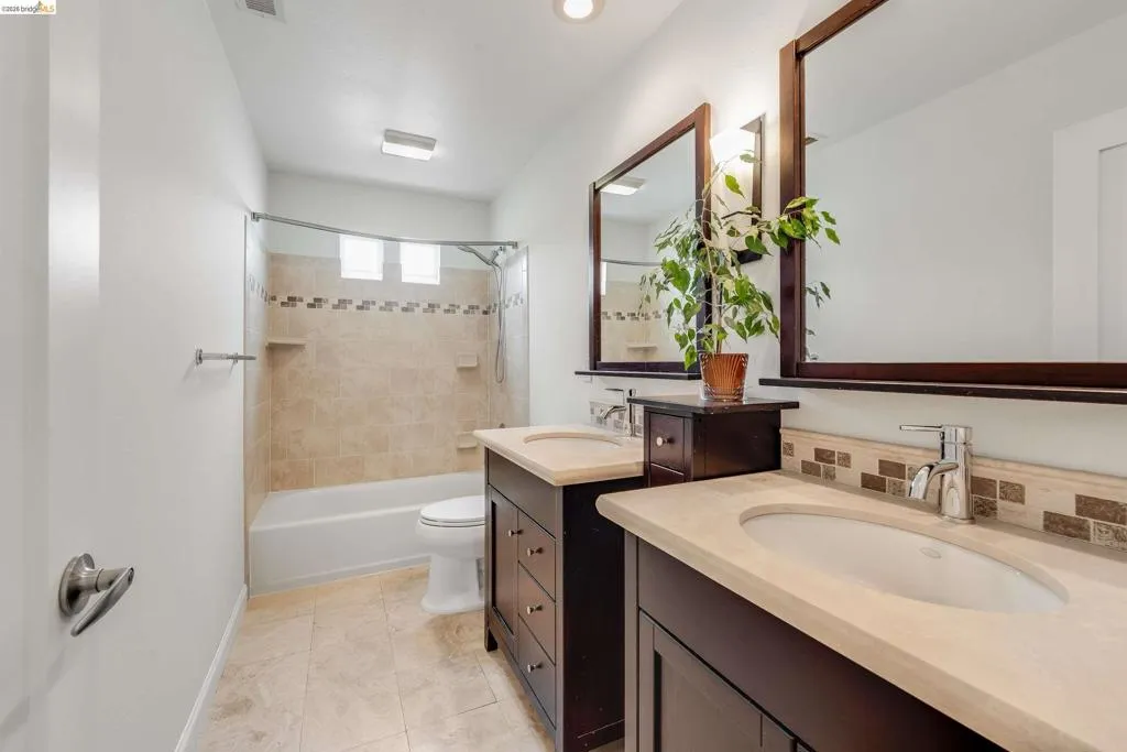 Bathroom featuring dual vanities with integrated sinks, stone countertops, and dark wood-finish cabinetry