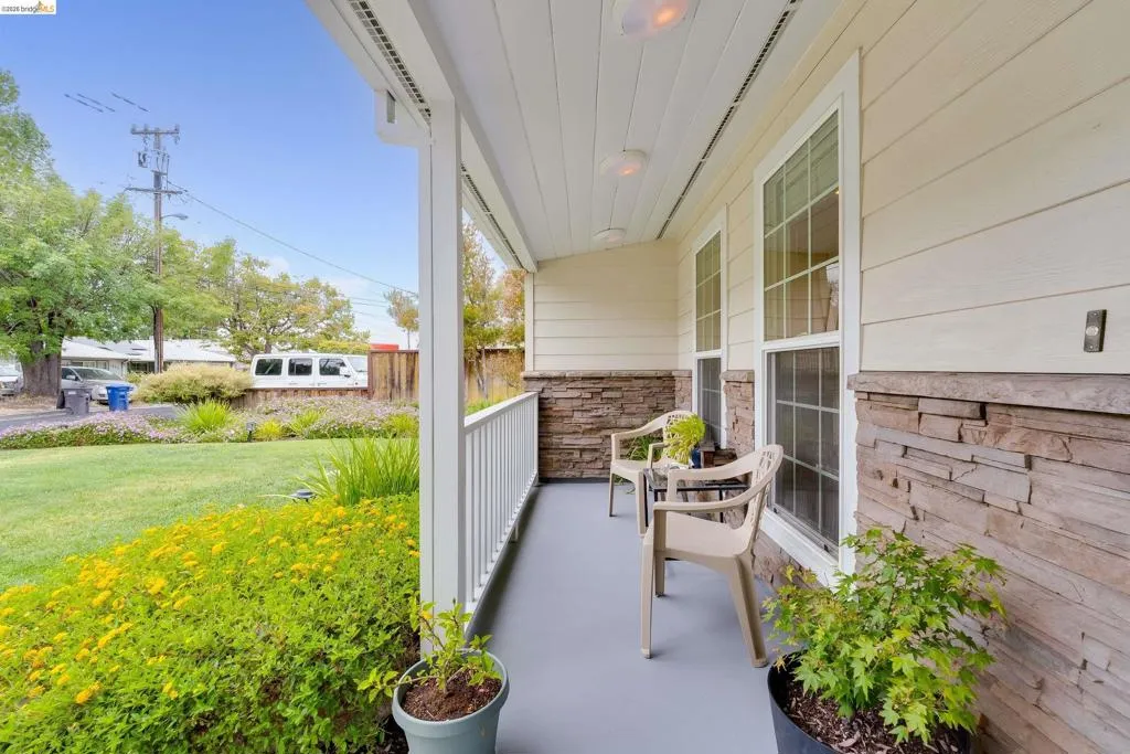 Covered front porch featuring a stacked stone façade, horizontal siding, white railings, and recessed ceiling lighting