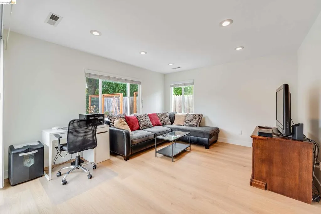 Spacious room featuring light wood-finish flooring, recessed lighting, and multiple windows