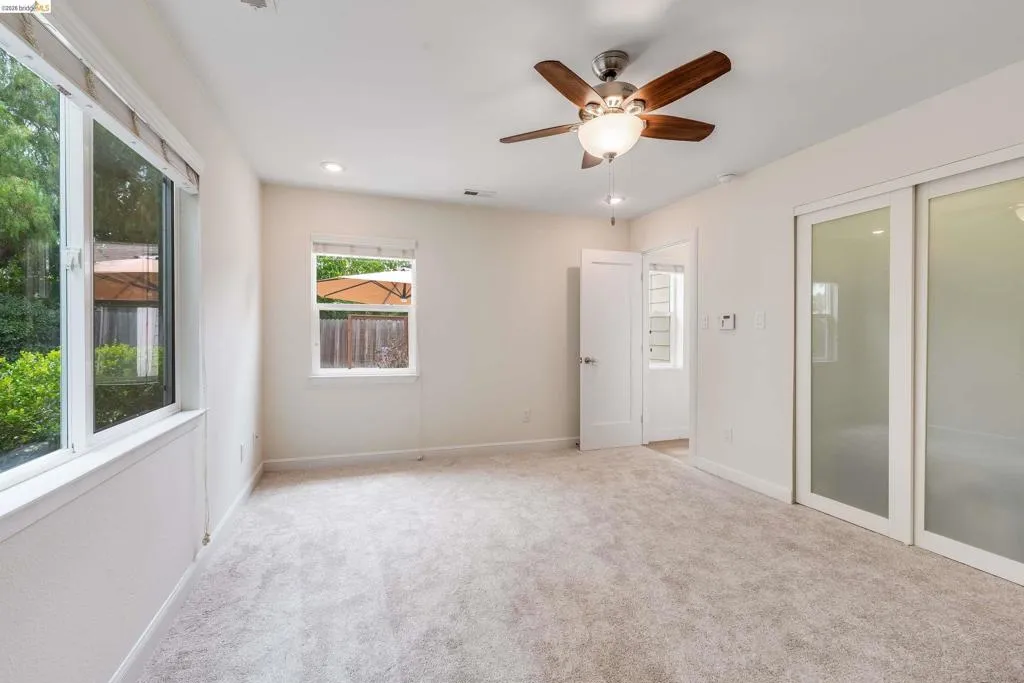 Carpeted room featuring a ceiling fan with light fixture, recessed lighting, and two windows