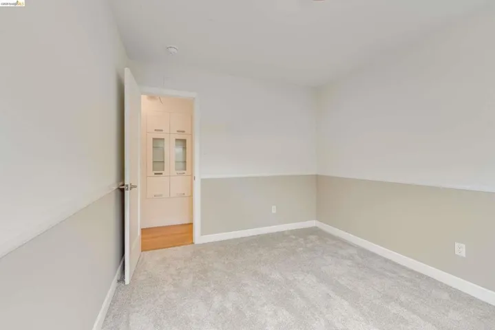 Carpeted room featuring a two-tone wall treatment with a neutral lower panel and white upper section