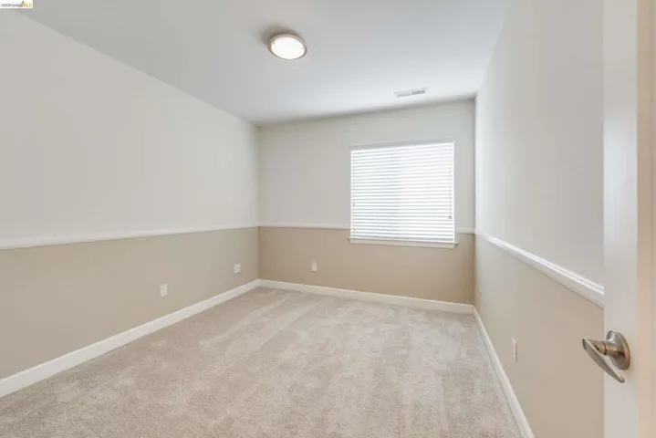 Carpeted interior space featuring a single window with blinds, a flush-mount ceiling light fixture, and two-tone wall finishes