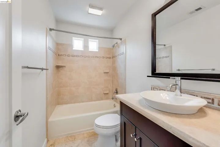Bathroom featuring a vanity with an oval vessel sink, chrome faucet, and a stone-finish countertop