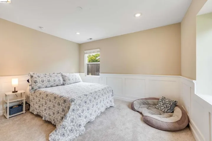 Carpeted room featuring wainscoting, recessed lighting, and a window with natural light