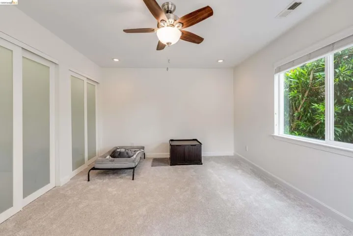 Light-filled room featuring a ceiling fan with integrated lighting, recessed lighting, and a large window with white trim
