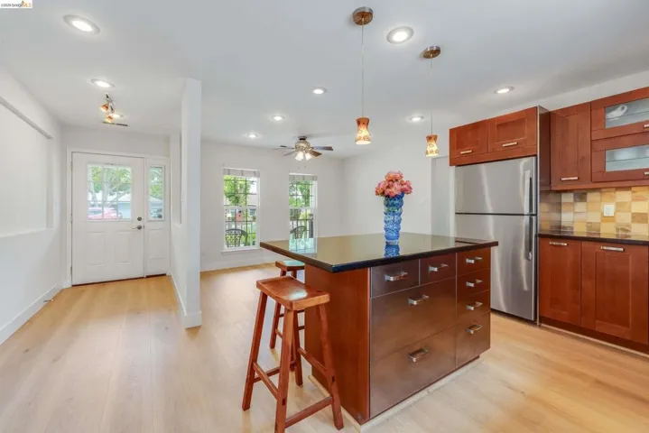 Open-concept kitchen and living area featuring light wood-finish flooring, recessed lighting, and a kitchen island with a dark countertop