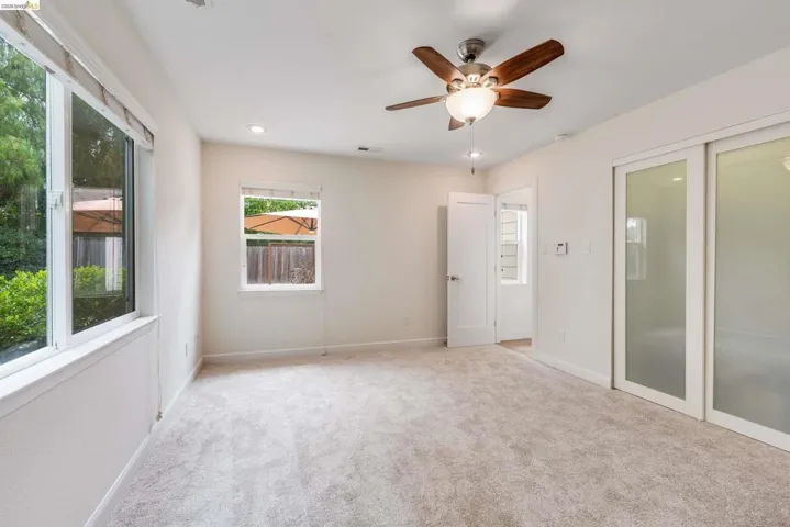 Carpeted room featuring a ceiling fan with light fixture, recessed lighting, and two windows