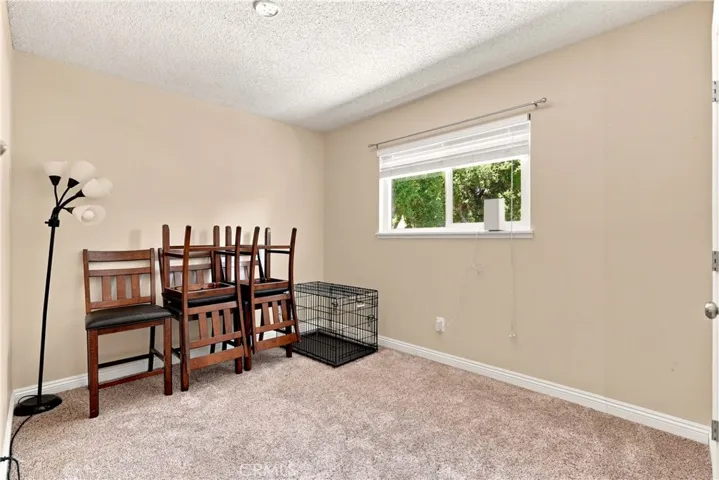Bedroom 4 has plush carpet and a window that overlooks the backyard.