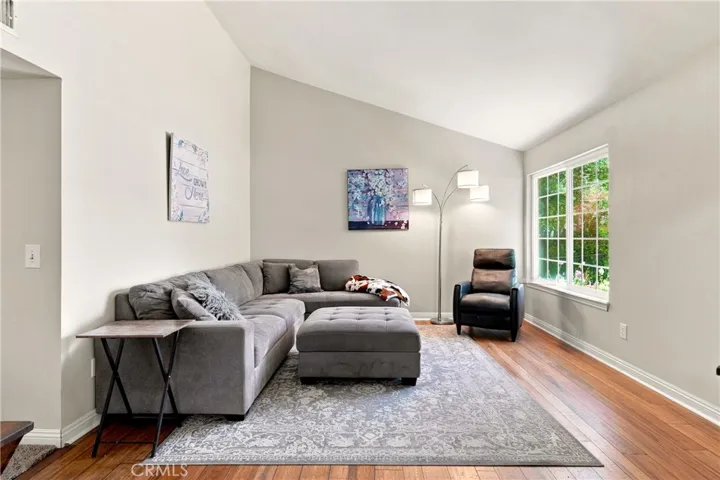 The living room boasts vaulted ceilings and a large window that give it a light and airy feel.