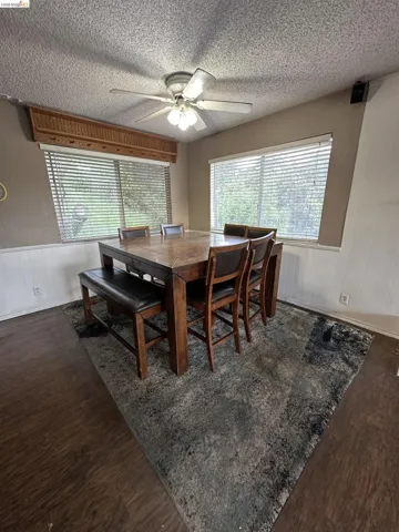 Dining area featuring wood-finish flooring, two large windows with blinds, and wainscoting