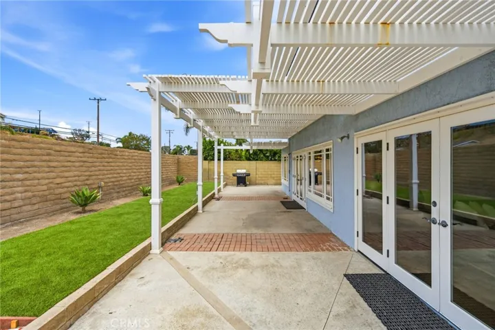 Vinyl patio cover spans the width of the home for added shade and artificial turf adds low-maintenance outdoor space to the backyard.
