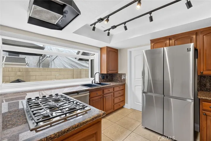Stainless steel appliances, including a gas cookstop complement the kitchen’s warm finishes.