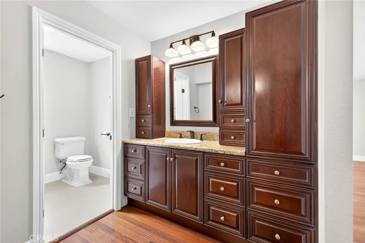 Private vanity area features rich cabinetry and granite countertops.

