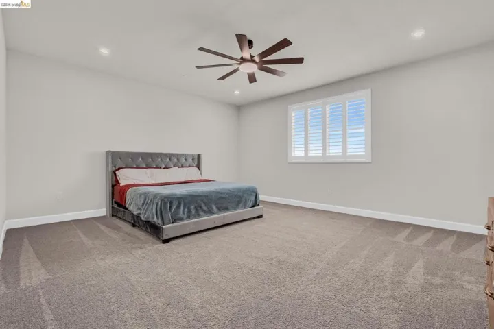 Spacious room featuring neutral carpeting, light gray wall paint, and white baseboards