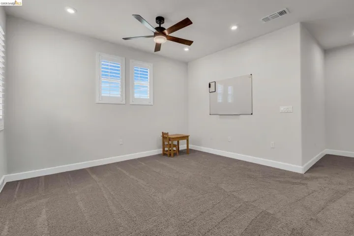 Recessed ceiling lighting complements the central ceiling fan in this room featuring plush carpeting
