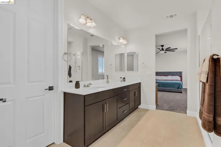 Dual sink vanity with dark wood-finish cabinetry, white countertops, and brushed nickel fixtures