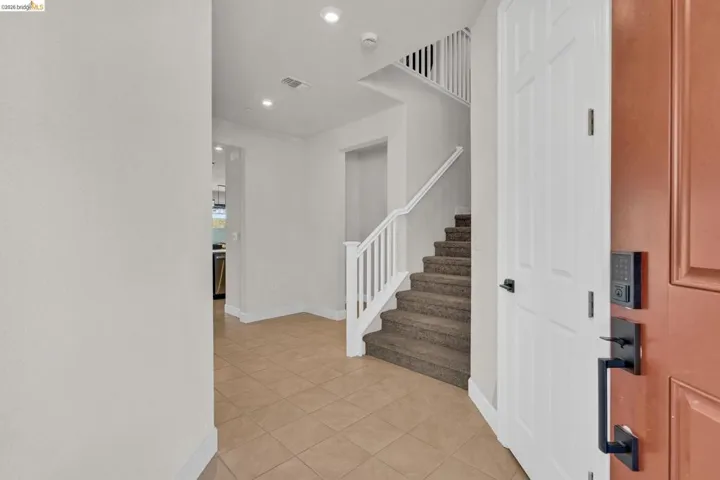 Entryway featuring a staircase with white balusters and carpeted treads, recessed lighting, and tile flooring