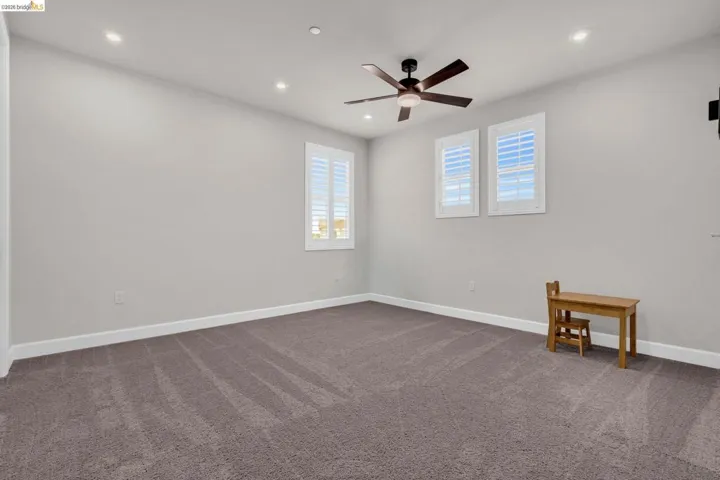 Spacious room featuring neutral carpeting, recessed lighting, and a ceiling fan