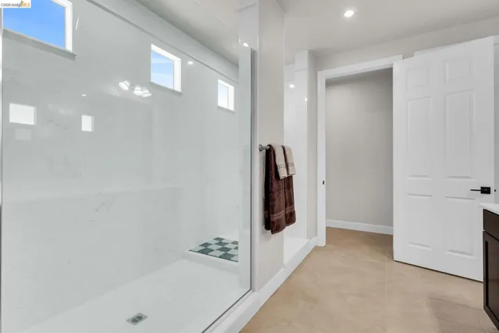 Spacious walk-in shower with clear glass enclosure and white subway tile base