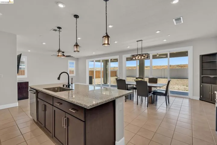 Kitchen island featuring a granite countertop, undermount sink, and dark wood cabinetry
