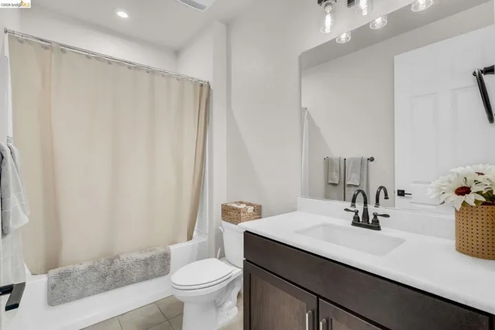 Contemporary bathroom featuring a dark wood-finish vanity with a white countertop, undermount sink, and matte black faucet