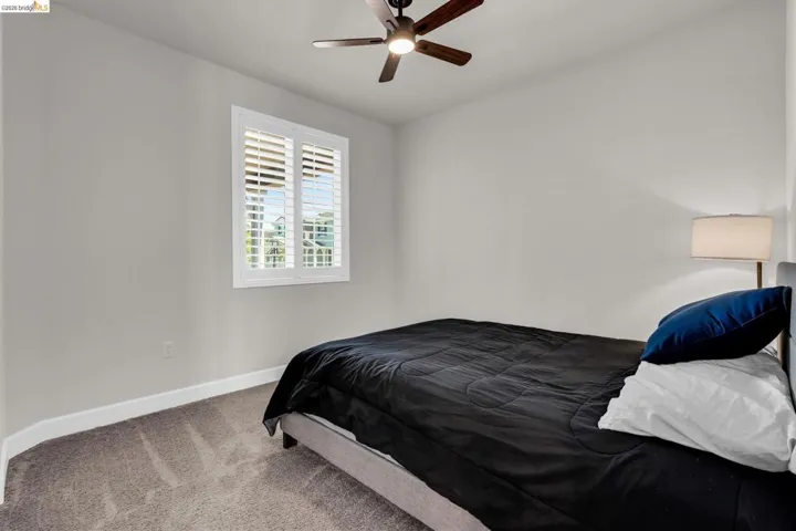 Room featuring neutral wall tones, gray carpeting, and a window with white plantation shutters