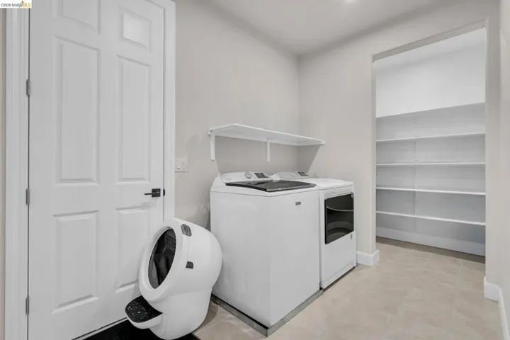 Laundry area featuring a side-by-side washer and dryer, an overhead shelf, and a pantry with built-in shelving