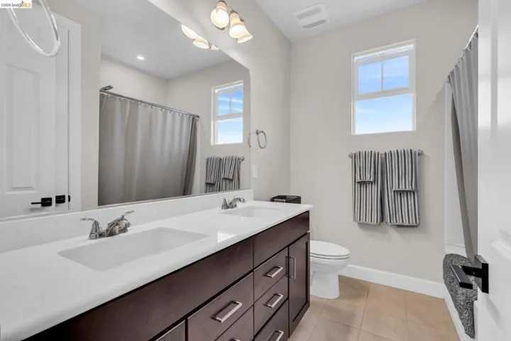 Bathroom featuring a dual-sink vanity with dark wood-finish cabinetry and a light-toned countertop
