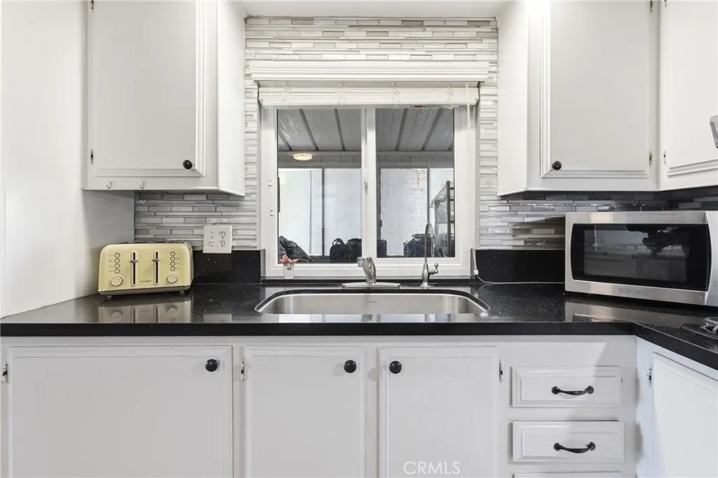 The kitchen features sleek black Quartz countertops and crisp white cabinetry.