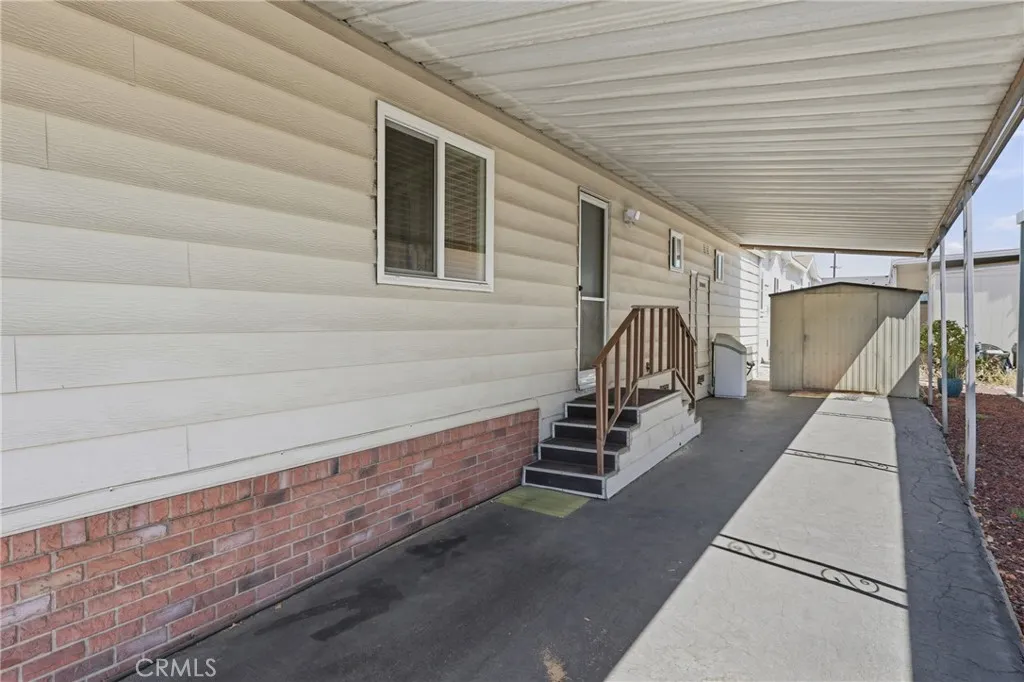 Covered tandem parking for two vehicles on a paved surface, with convenient secondary access through the laundry room and an included storage shed.