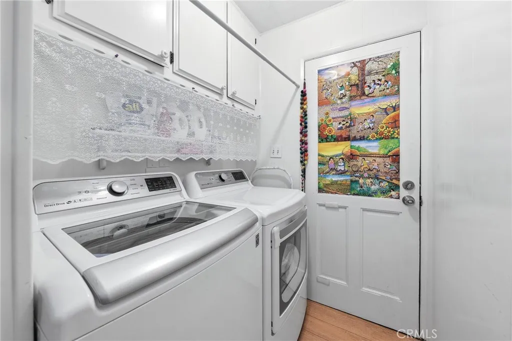 A spacious laundry room featuring a washer, dryer, ample storage, and convenient direct access to the carport.
