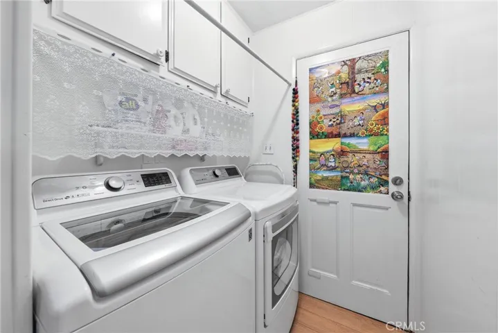 A spacious laundry room featuring a washer, dryer, ample storage, and convenient direct access to the carport.