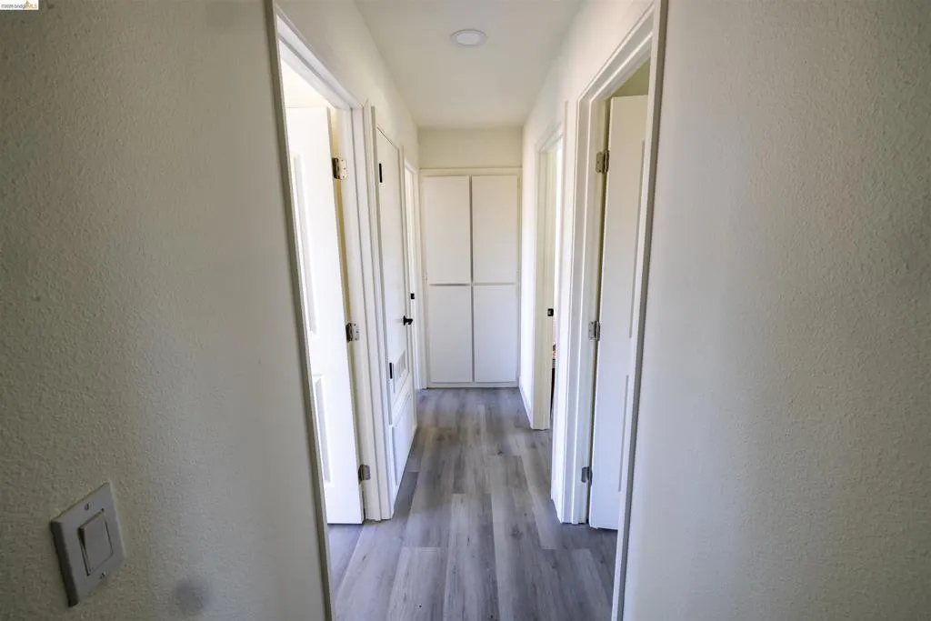 Hallway featuring wood-finish flooring, recessed lighting, white panel doors, and built-in white cabinetry