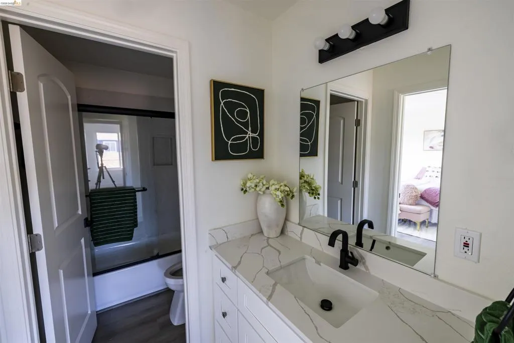 Bathroom vanity featuring a rectangular undermount sink, a stone-finish countertop, and a matte black faucet