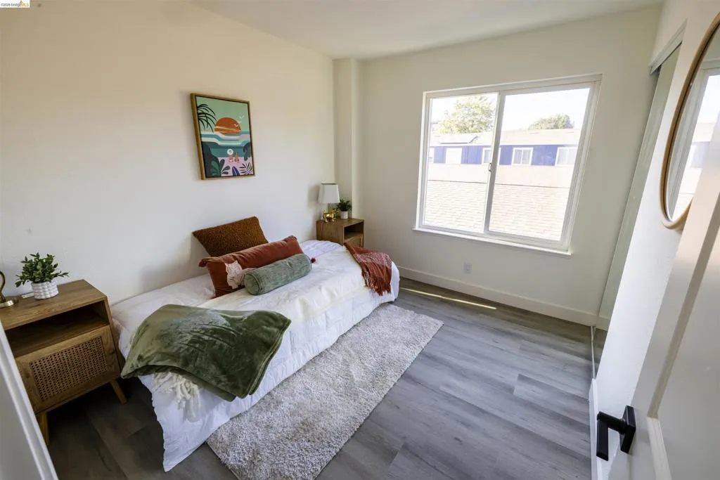 Room featuring a large window, light gray wood-finish flooring, white walls, and a white baseboard