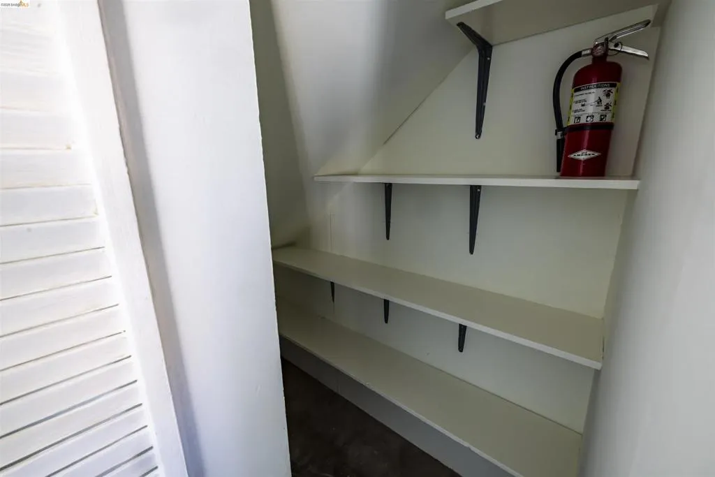 Built-in shelving unit featuring multiple white shelves with dark support brackets, set against a light-colored wall