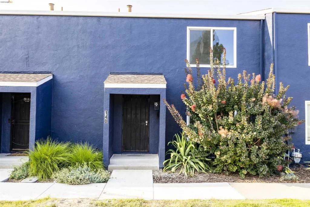 Blue stucco exterior featuring a covered entry, black security door, and a second-story window