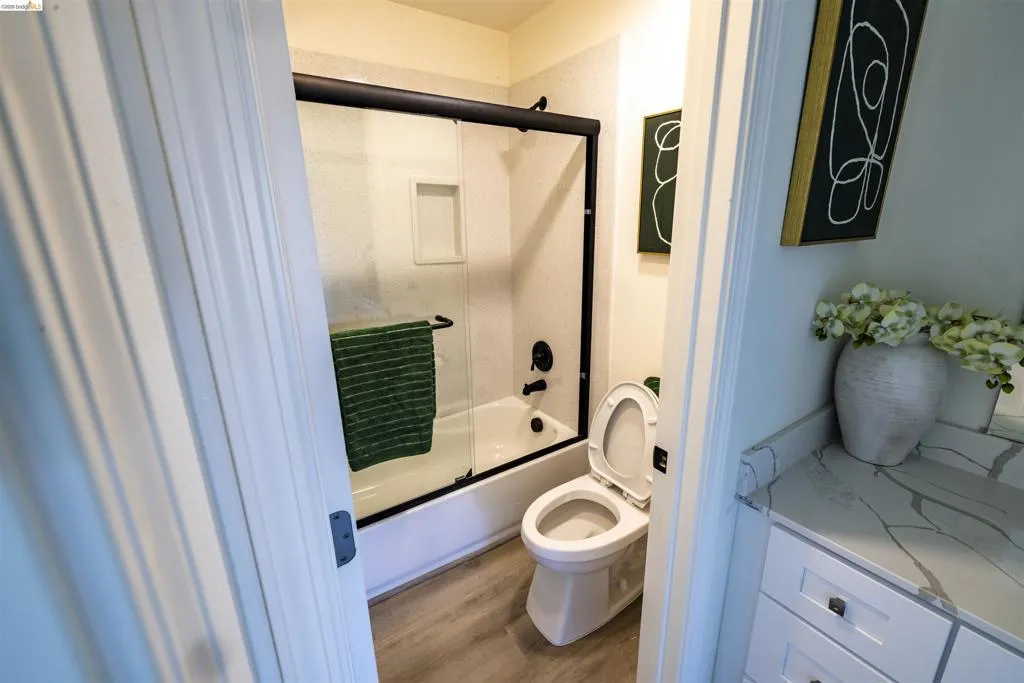 Bathroom featuring a white tub with a black-framed glass shower enclosure, black plumbing fixtures, and a recessed shower niche