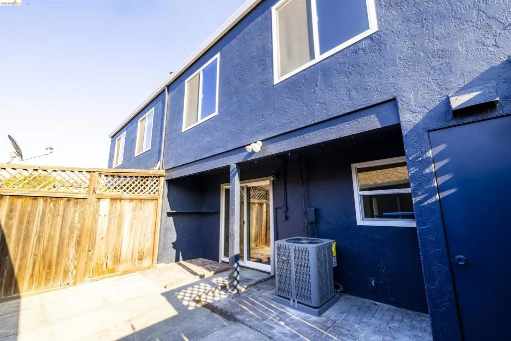 Rear exterior featuring a blue stucco finish and wood fencing