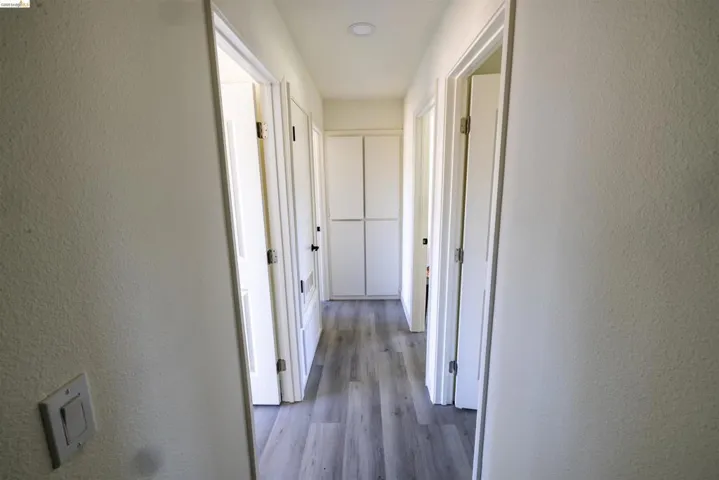 Hallway featuring wood-finish flooring, recessed lighting, white panel doors, and built-in white cabinetry