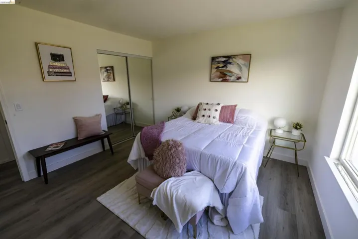 Room featuring wood-finish flooring, a full-height window, and light-toned walls