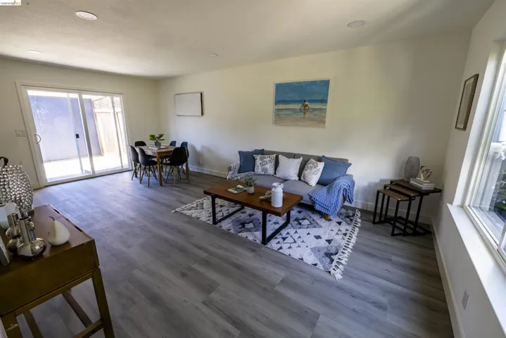 Spacious open-concept living area featuring light-toned walls, recessed lighting, and wood-finish flooring