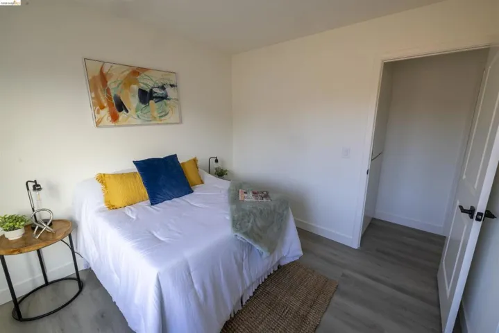 Bedroom featuring light gray wood-finish flooring, white walls, and a visible closet entry