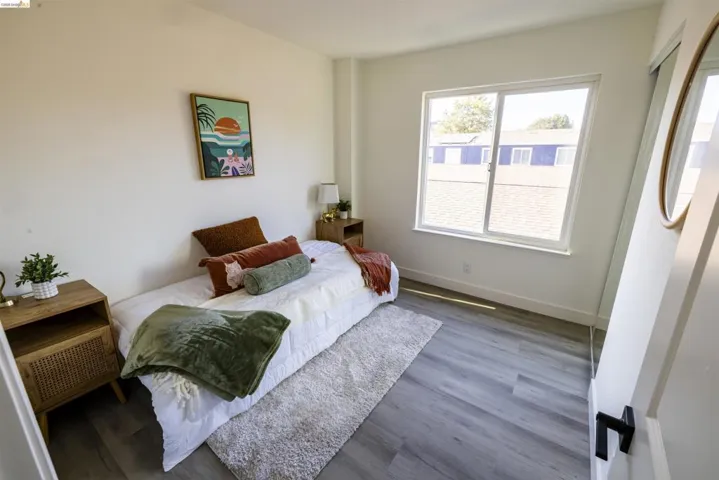 Room featuring a large window, light gray wood-finish flooring, white walls, and a white baseboard