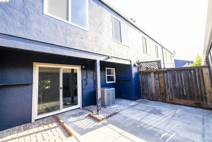Rear exterior featuring dark blue stucco siding, white-framed windows, and a sliding glass door
