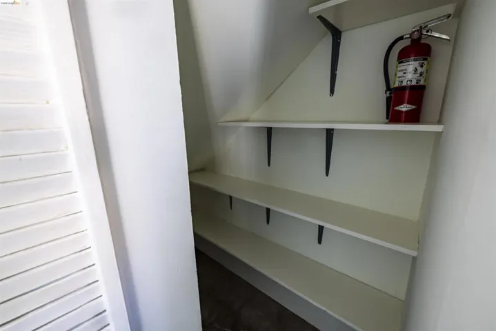 Built-in shelving unit featuring multiple white shelves with dark support brackets, set against a light-colored wall