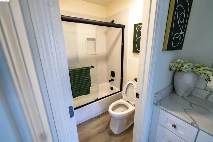 Bathroom featuring a white tub with a black-framed glass shower enclosure, black plumbing fixtures, and a recessed shower niche