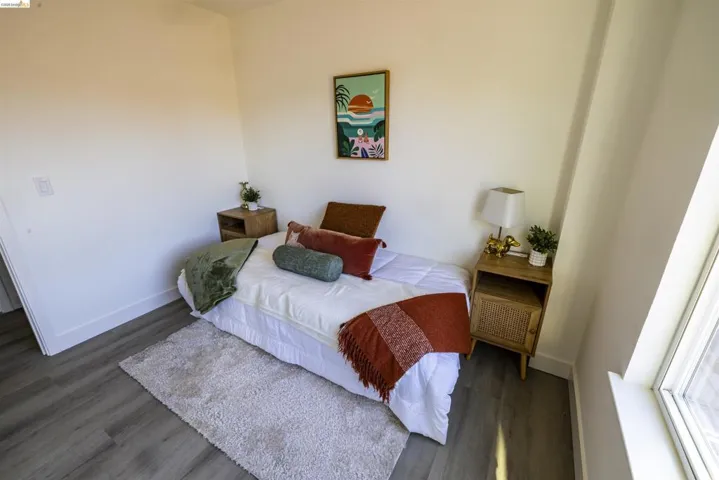 Bedroom featuring light wood-finish flooring, white walls, and a window with natural light