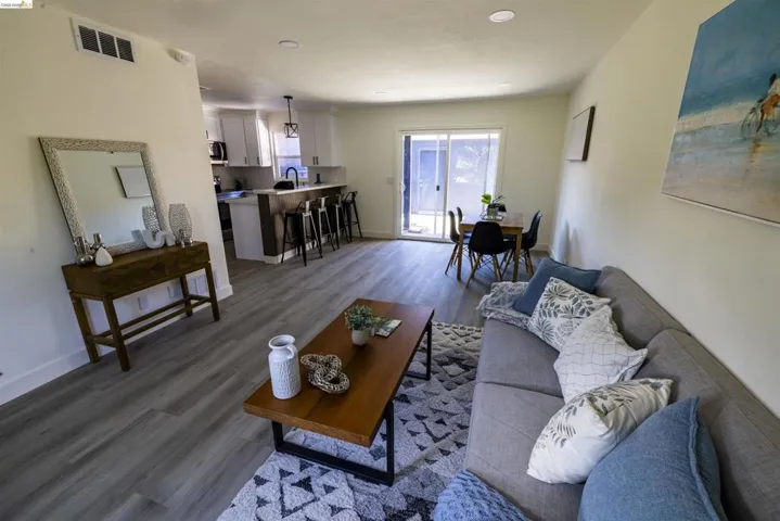 Open-concept living area featuring wood-finish flooring, recessed lighting, a kitchen with a breakfast bar, and a dining area with sliding glass doors